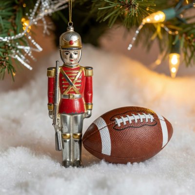 A painted tin soldier Christmas ornament standing beside a miniature football